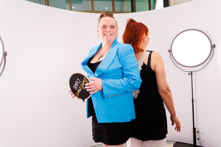 Two guests pose back to back beside a circular light on the video booth set.
