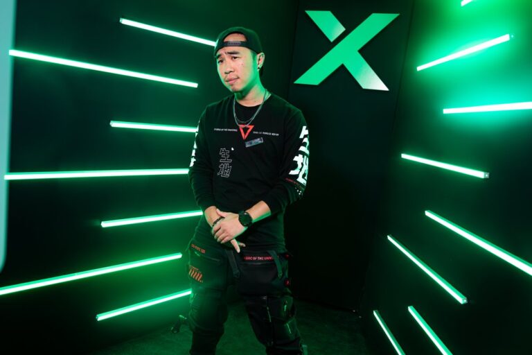 Guest wearing a cap poses alone inside a booth with green light strips.