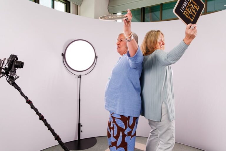 Two guests raise their arms on the 360 set beside a circular light.