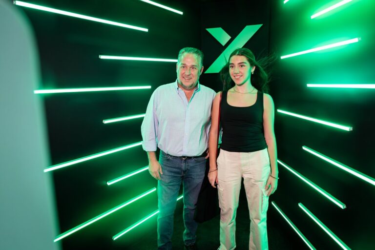 Two guests pose inside a booth lined with bright green LED lights.