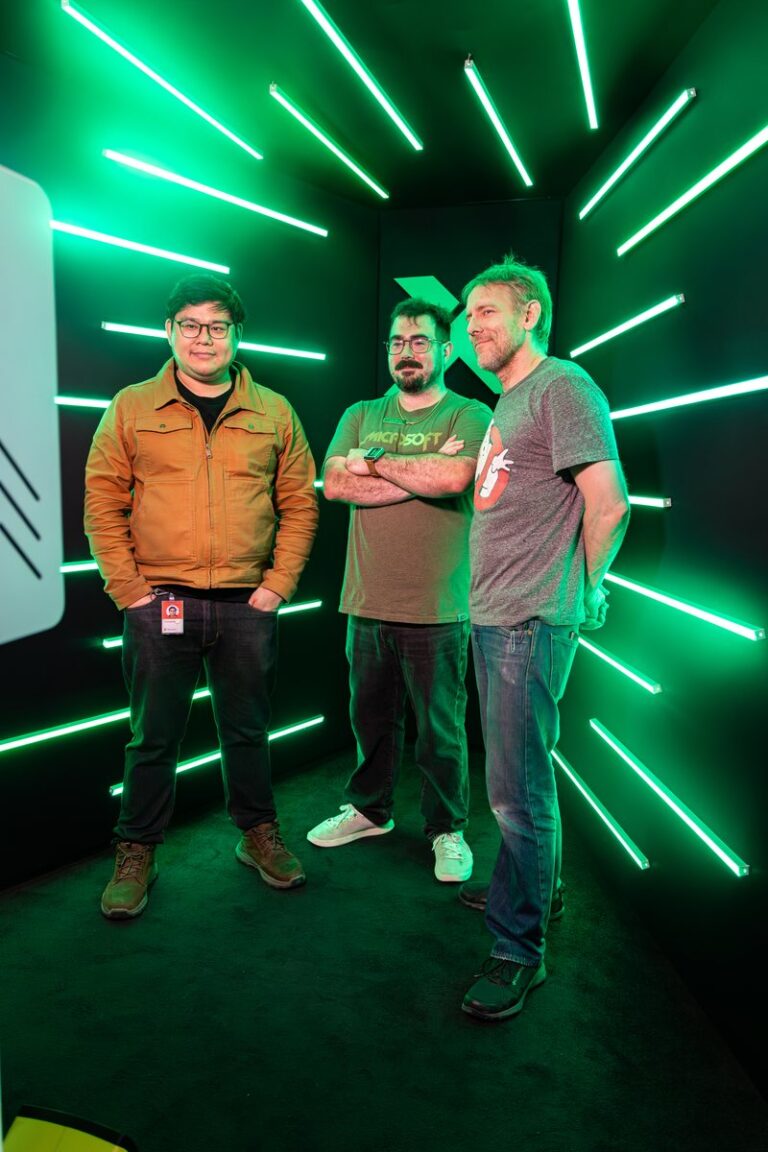 Three guests stand together inside the illuminated green LED booth.