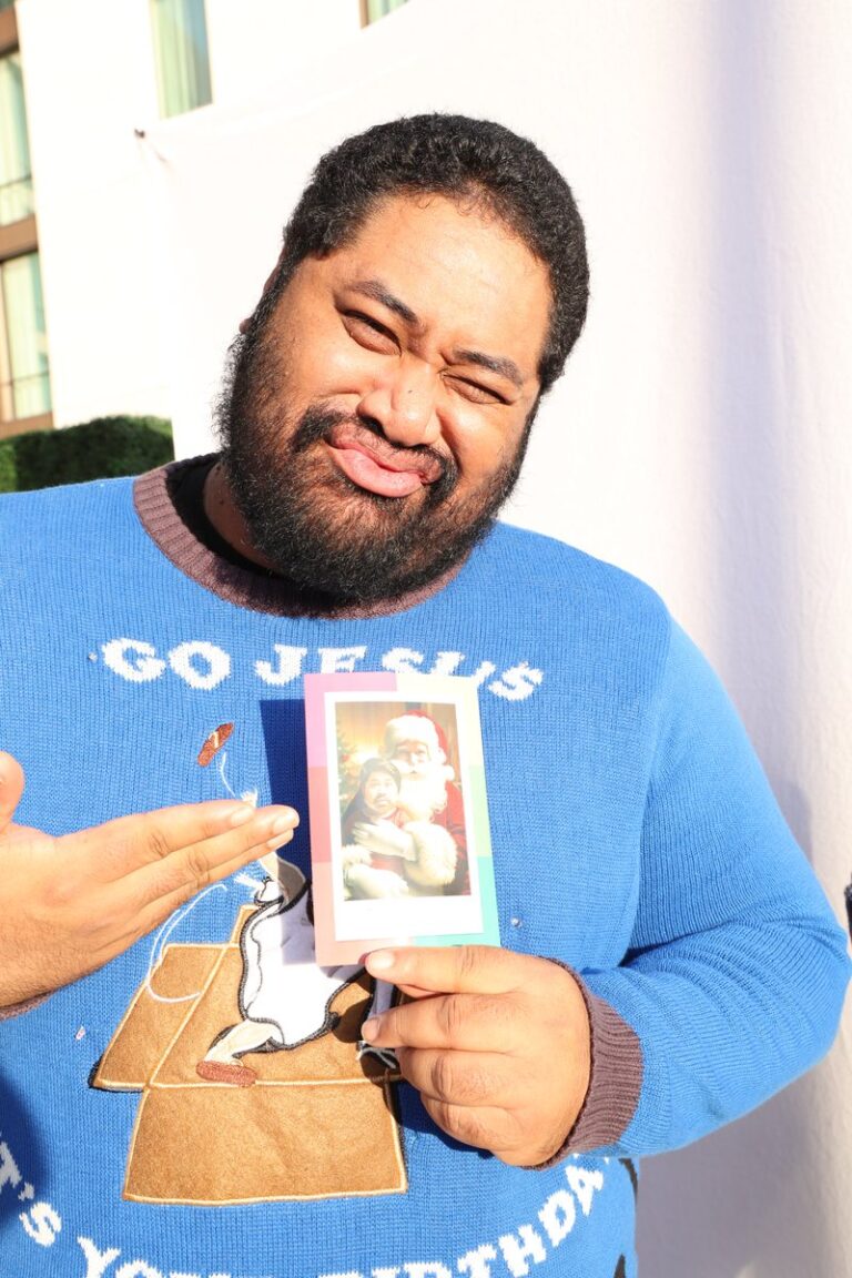 Guest in a blue T-shirt holds a colorful illustrated portrait print.