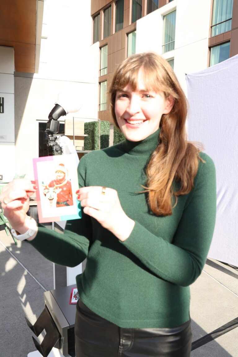 Guest in a green top shows a colorful portrait print beside the booth.