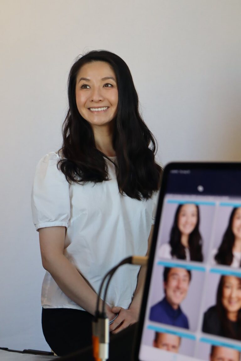 Guest in a light top smiles beside a tablet displaying portrait previews.