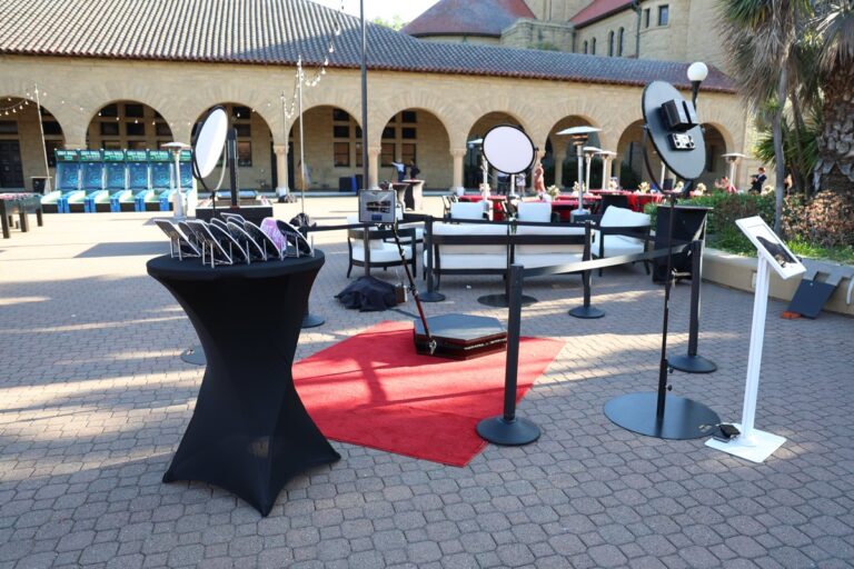 Miami Photo Booth Rental 2 Outdoor 360 video platform on a red carpet, surrounded by lights and barrier posts.