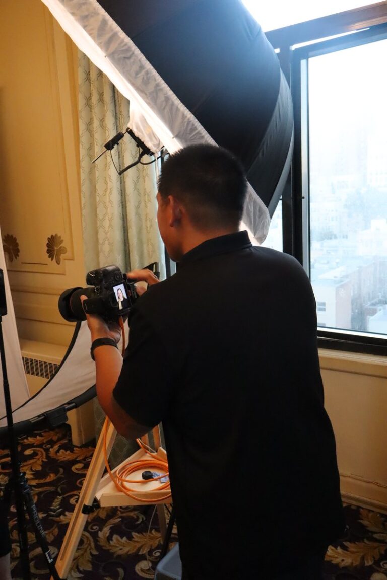 Photographer works beside a camera and large softbox in an indoor portrait setup.
