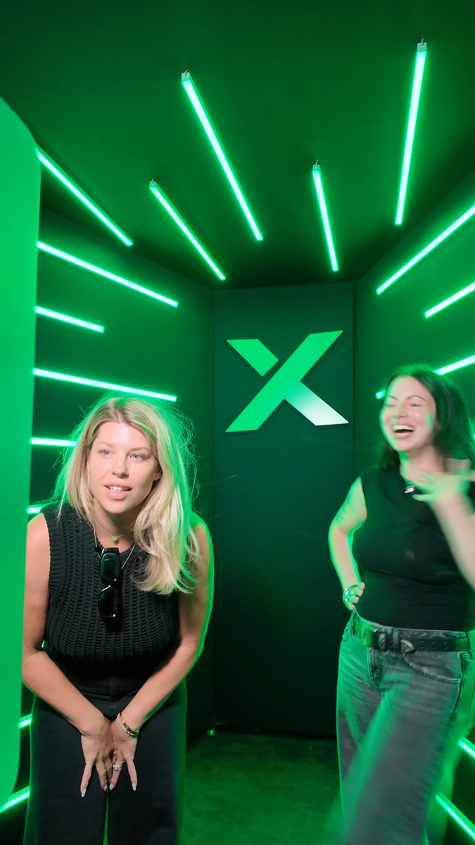 Two guests strike playful poses inside the green LED booth.