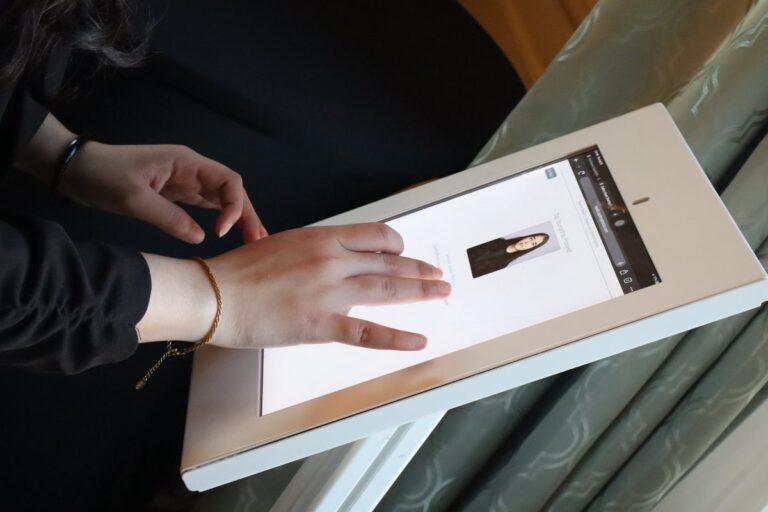 Hands select a portrait on a tablet in a white presentation frame.