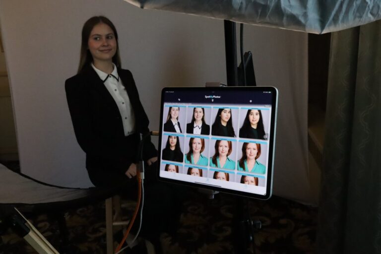 Guest in a dark jacket stands beside a screen showing several portrait selections.
