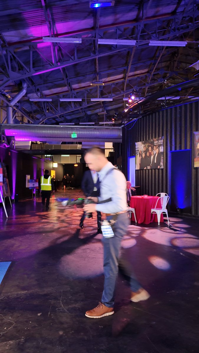 Portland Photo Booth Rental 4 Photographer bends forward to frame a shot in a purple-lit event space.