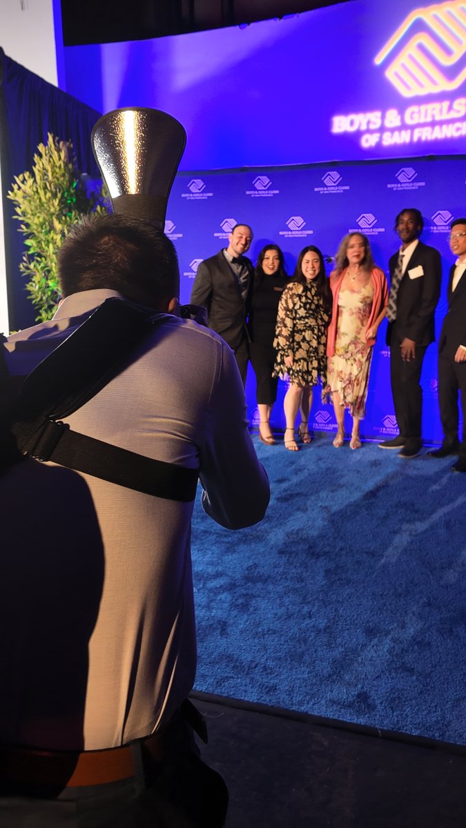 Photographer photographs a group in a purple-lit event space.