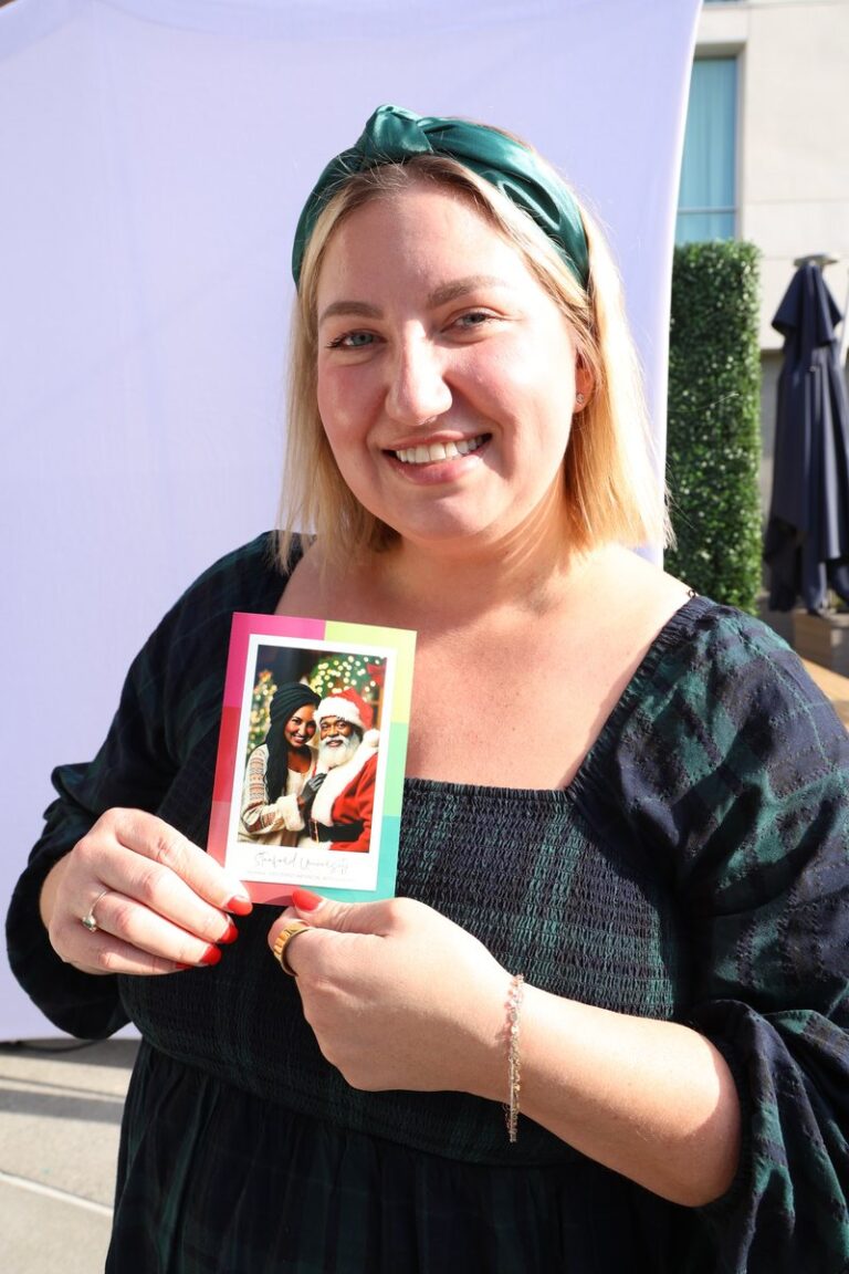 Smiling guest in a dark cardigan holds an illustrated portrait print.